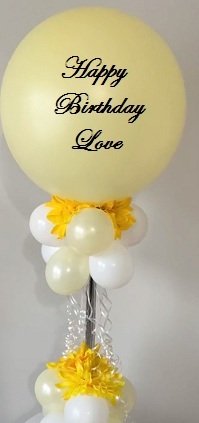 Transparent Balloon Printed Happy Birthday LOVE Tied with balloons and yellow gerberas at base of balloon to a basket of 6 white balloons 6 yellow gerberas